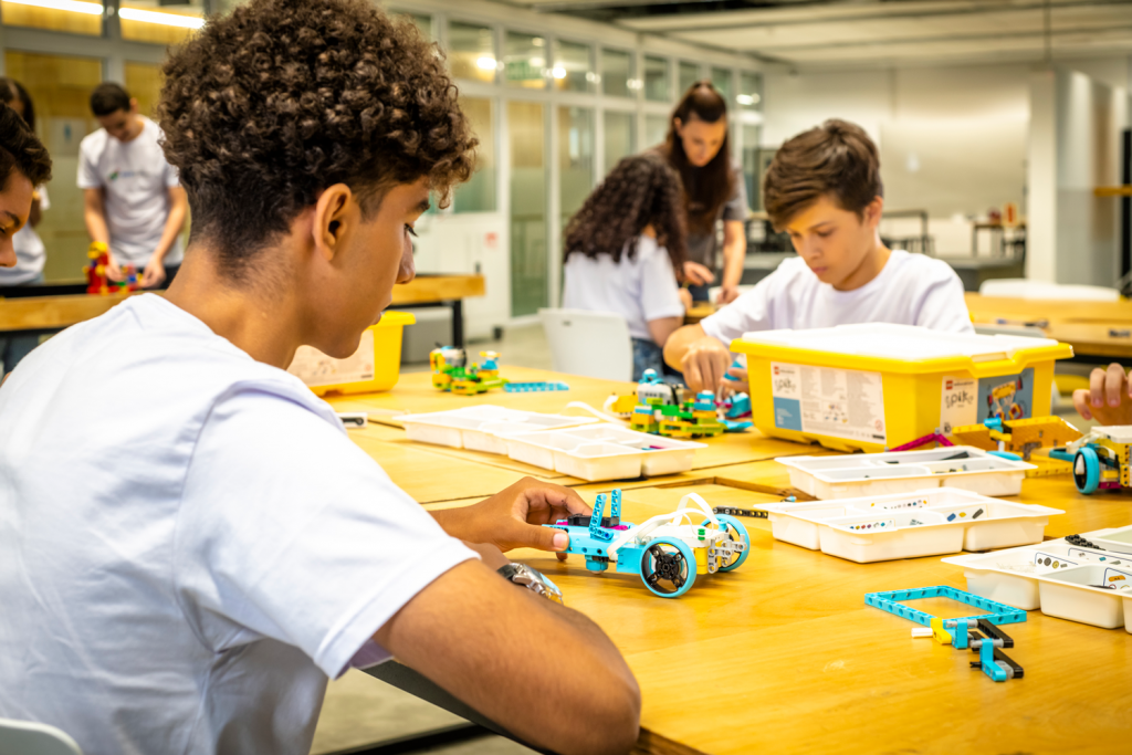 Alunos trabalhando com kits de robótica em sala maker